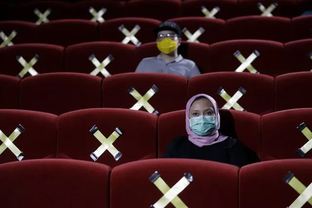 People sit near seats marked for physical distancing at Cinepolis movie theatre following the ease of coronavirus restrictions in Jakarta, Indonesia, 23 October 2020. Jakarta's administrations allows movie theaters to resume their operations with 25 percent capacity following the ease of COVID-19 pandemic restrictions. (Photo by Mast Irham/EPA/EFE)