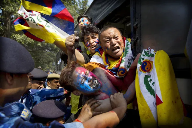 Indian para-military force soldiers push exiled Tibetan activists into a police bus during a protest outside the Chinese Embassy, in New Delhi, India, Friday, March 9, 2018. The protest was to mark the 59th anniversary of the March 10, 1959, Tibetan Uprising Day, against the Chinese rule, which was brutally quelled by the Chinese army forcing the spiritual leader the Dalai Lama and thousands of Tibetans into exile. (Photo by Manish Swarup/AP Photo)