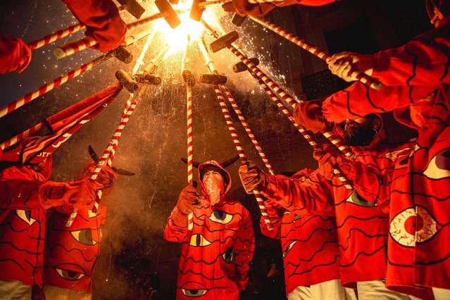 Fire runners in devil costumes gather to enlighten their stick mounted firecrackers celebrating the 30th anniversary of the “Diables de les Corts” in Barcelona, Spain on May 25, 2024. (Photo by Matthias Oesterle/Alamy Live News)