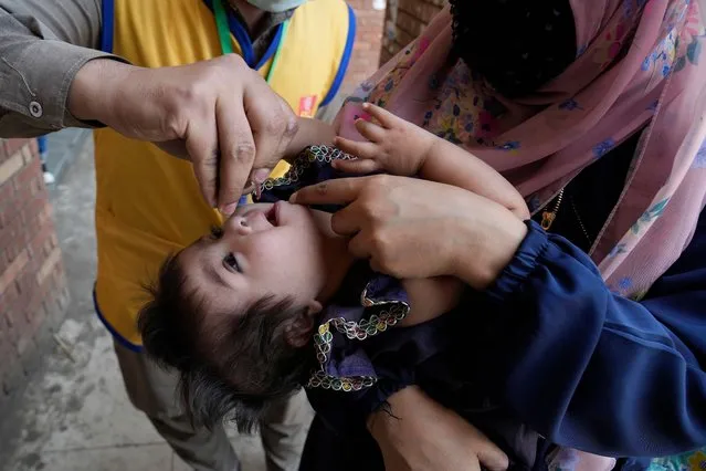 A health worker administers a polio vaccine to a child in Lahore, Pakistan, Monday, March 13, 2023. Pakistan is launching anti-polio campaign targeting millions children under the age of five. It is one of two countries in the world where polio continues to threaten the health and well-being of children. (Photo by K.M. Chaudary/AP Photo)