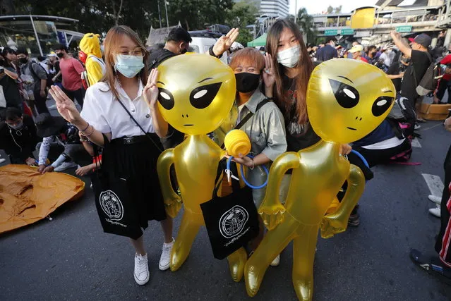 Protesters flash three-finger protest gestures while holding balloons shaped like aliens – to mock accusations that foreigners fund and direct their movement - during a rally Friday, November 27, 2020 in Bangkok, Thailand. (Photo by Sakchai Lalit/AP Photo)