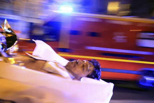 A man is being evacuated from the Bataclan theater after a shooting in Paris, November 13, 2015. (Photo by Thibault Camus/AP Photo)