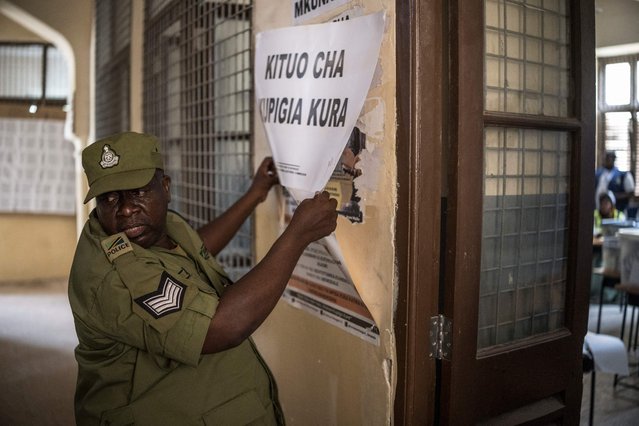 A Tanzanian police officer tears down a voting station poster before the beginning of the counting operations in Stone Town, on October 29, 2025. Polls opened on October 29, 2025 in Tanzania elections in which the main challengers were either jailed or barred from running, with rights groups decrying a “wave of terror”. President Samia Suluhu Hassan, 65, is determined to cement her position with an emphatic victory that will silence critics within her own party, analysts say. (Photo by Marco Longari/AFP Photo)