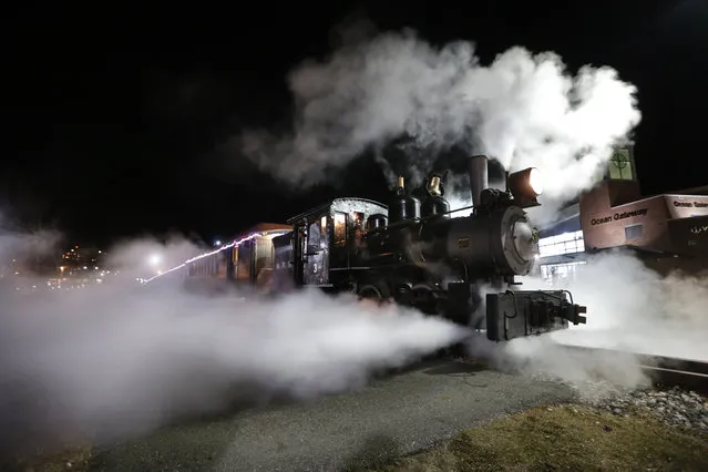 Steams shoots out from a 1913 steam locomotive as the Polar Express begins it's journey to the "North Pole" on the Maine Narrow Gauge Railroad, Friday, November 27, 2015, in Portland, Maine. The popular train ride, based on the well-known children's book, has rides scheduled throughout the holiday season. Passengers ride about a mile and a half along Casco Bay on the Eastern Promenade to the "North Pole". (Photo by Robert F. Bukaty/AP Photo)