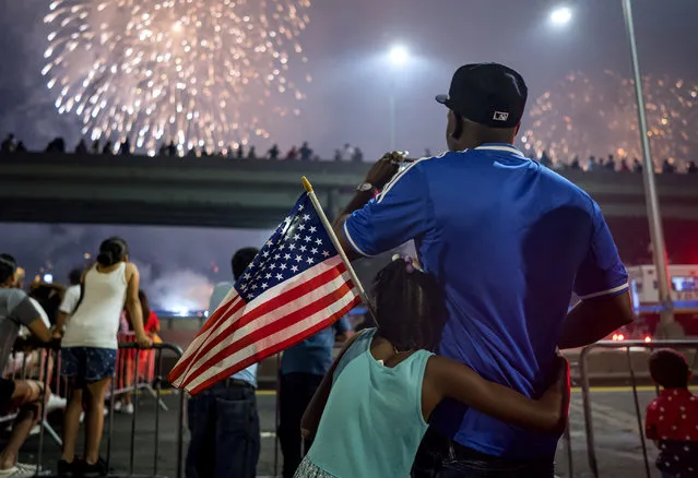 Deon Stewart and his daughter Semiyah, of New York, join other spectators as they watch a fireworks display on the east side of Manhattan, part of Independence Day festivities Wednesday, July 4, 2018, in New York. (Photo by Craig Ruttle/AP Photo)