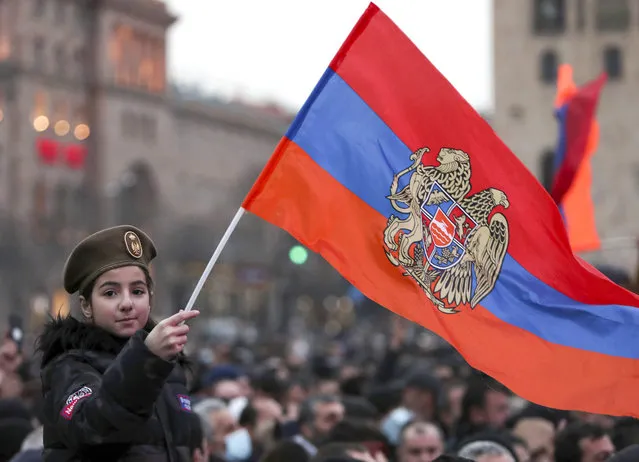 A girl waves an Armenian national flag during a rally of supporters of Armenian Prime Minister Nikol Pashinyan rally in the center of Yerevan, Armenia, Monday, March 1, 2021. Amid escalating political tensions in Armenia, supporters of the country's embattled prime minister and the opposition are staging massive rival rallies in the capital of Yerevan. Prime Minister Nikol Pashinyan has faced opposition demands to resign since he signed a peace deal in November that ended six weeks of intense fighting with Azerbaijan over the Nagorno-Karabakh region. (Photo by Hayk Baghdasaryan/PHOTOLURE via AP Photo)
