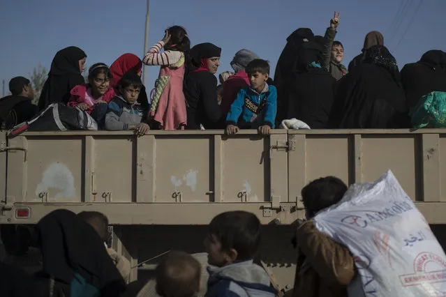 Women and children displaced by fighting between Iraqi forces and Islamic state militants stand inside a truck as they wait to be taken out of Mosul, Iraq, Friday, November 18, 2016. (Photo by Felipe Dana/AP Photo)