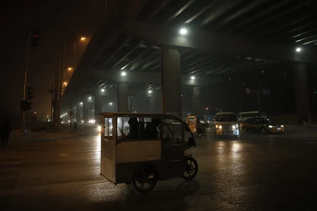 A motor tricycle runs on the road during a hazy day in Beijing, China, 20 December 2015. Beijing issued a red alert for smog on 18 December 2015, urging schools to close and residents to stay indoors for the second time in 10 days. Restrictions began on 19 December and will last until 22 December, the city's emergency management headquarters announced on the Beijing government website. (Photo by Wu Hong/EPA)