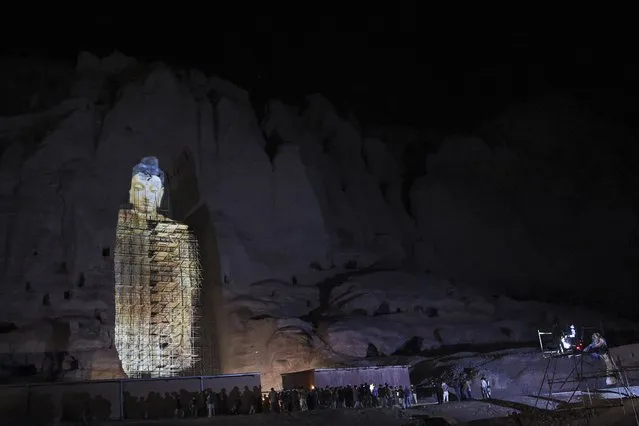 People watch a three-dimensional projection of the 56 metres-high Salsal Buddha at the site where the Buddhas of Bamiyan statues stood before being destroyed by the Taliban in March 2001, in Bamiyan province on March 9, 2021. (Photo by Wakil Kohsar/AFP Photo)