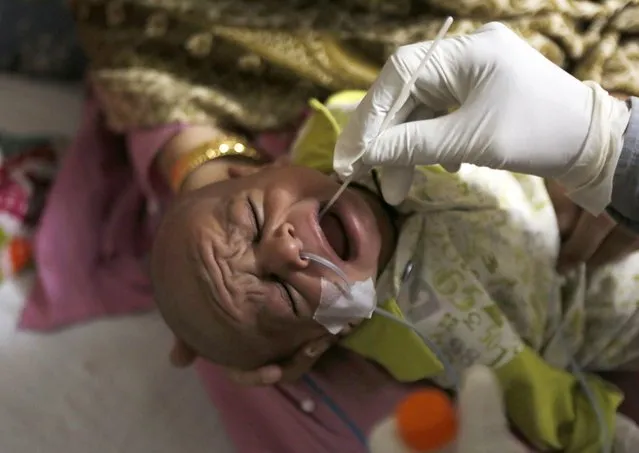 A health care worker takes a nasal swab sample from a child at a COVID-19 testing facility at a hospital in Lahore, Pakistan, Thursday, April 1, 2021. (Photo by K.M. Chaudary/AP Photo)