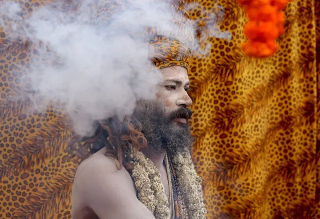 An Indian monk dressed as Lord Shiva takes holy smoke at a transit camp as pilgrims arrive for the upcoming Gangasagar Fair at Sagar Island, in Calcutta, eastern India, 07 January 2016. The Gangasagar Fair is an annual gathering of Hindu pilgrims during Makar Sankranti at Sagar Island, 130 km south of Calcutta in West Bengal, to take a dip in sacred waters of Ganga River before she merges in the Bay of Bengal. (Photo by Piyal Adhikary/EPA)