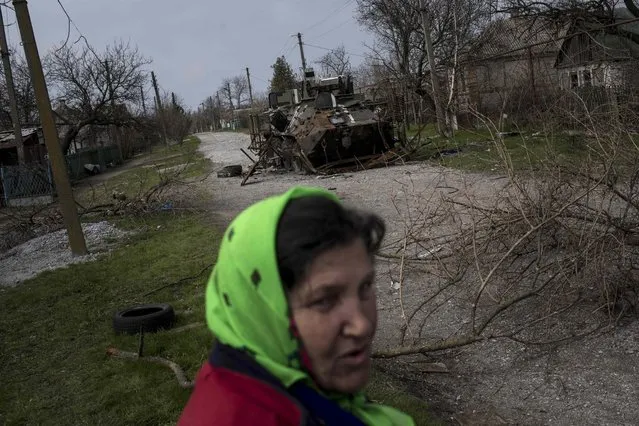 Local resident Lyudmila Kuzina walks near a damaged Ukrainian APC in the village of Shyrokyne, eastern Ukraine, Thursday, April 16, 2015. Shyrokyne, a village on the Azov Sea that has been the epicenter of recent fighting, has changed hands repeatedly throughout the conflict.  (AP Photo/Evgeniy Maloletka)