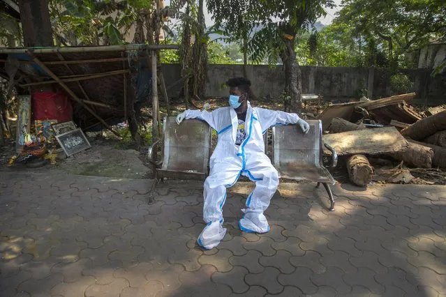 An exhausted health worker in protective suit takes rest after carrying a body of a person for cremation in Gauhati, India, Tuesday, April 27, 2021. Coronavirus cases in India are surging faster than anywhere else in the world. (Photo by Anupam Nath/AP Photo)