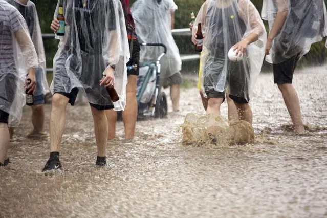 A group of young men walk in the rain on a flooded street in Wernigerode, Germany, Saturday, June 5, 2021. German authorities have issued severe weather warnings for parts of western Germany, a day after a man was killed and a 12-year-old girl was seriously injured in separate storm-related incidents. (Photo by Matthias Bein/dpa via AP Photo)