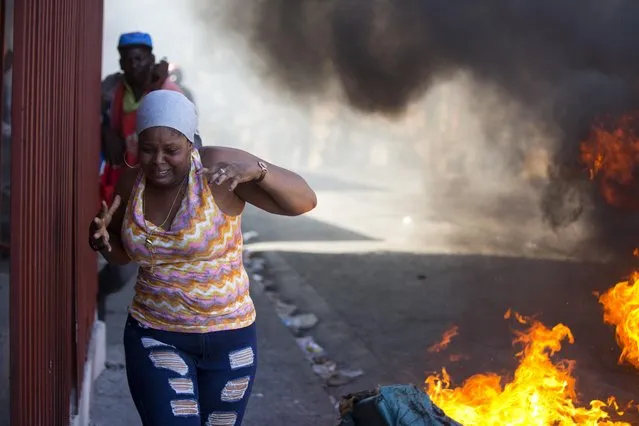 Residents run past burning barricades during a strike that is part of protests demanding to know how Petro Caribe funds have been used by the current and past administrations, in Port-au-Prince, Haiti, Monday, November 19, 2018. Much of the financial support to help Haiti rebuild after the 2010 earthquake comes from Venezuela's Petro Caribe fund, a 2005 pact that gives suppliers below-market financing for oil and is under the control of the central government. (Photo by Dieu Nalio Chery/AP Photo)