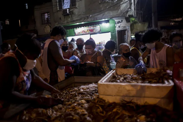 Residents receive crabs donated by the Viva Jacarezinho NGO, in the Jacarezinho favela of Rio de Janeiro, Brazil, Monday, July 12, 2021, amid the COVID-19 pandemic. (Photo by Bruna Prado/AP Photo)
