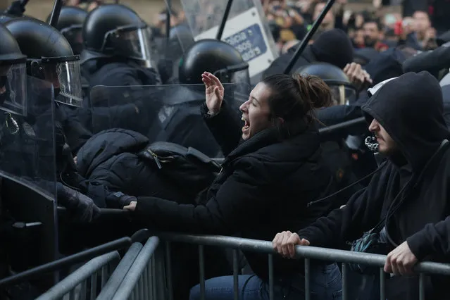 Members of the Catalan regional police force Mossos d'Esquadra try to keep protesters behind crowd control barricades during scuffles at a Catalan pro-independence demonstration in Barcelona on December 21, 2018 as the Spanish cabinet held a meeting in the city. Catalan pro-independence groups blocked roads in the region to protest the meeting. The weekly cabinet meeting usually takes place in Madrid but the government decided to hold it in the Catalan capital as part of its efforts to reduce tensions in Catalonia, which last year made a failed attempt to break away from Spain. (Photo by Pau Barrena/AFP Photo)