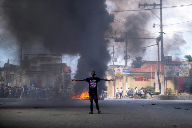 A man stands in front of a burning barricade on street filled with smoke from burning tires during a protest against the assassination of Haitian President Jovenel Moise in Cap-Haitien, Haiti July 22, 2021. (Photo by Ricardo Arduengo/Reuters)