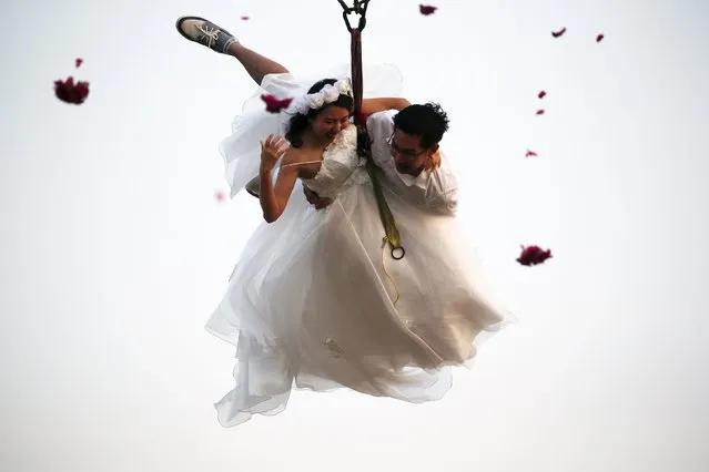 Bride Duangreuthai Amnuayweroj and groom Kasemsak Jiranantiporn fly while attached to cables during a wedding ceremony ahead of Valentine's Day at a resort in Ratchaburi province, Thailand, February 13, 2016. Four Thai couples took part in the wedding ceremony arranged by the resort. (Photo by Athit Perawongmetha/Reuters)