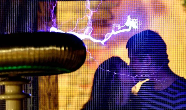This photo taken late on February 13, 2016 shows a couple exchanges a kiss by a Faraday cage displaying electrical sparks of Tesla coil, on the eve of Valentine's Day at the Elemento Science Museum in Minsk. (Photo by Maxim Malinovsky/AFP Photo)
