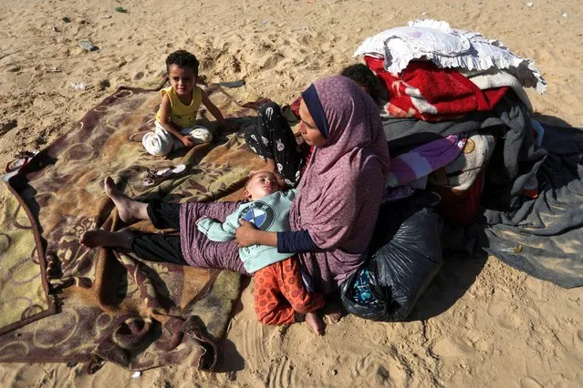 A woman sits with children outside, as displaced Palestinians, who fled their houses due to Israeli strike, shelter in a camp in Rafah, amid the ongoing conflict between Israel and Palestinian Islamist group Hamas, in the southern Gaza Strip on December 6, 2023. (Photo by Ibraheem Abu Mustafa/Reuters)