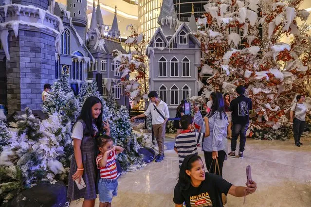 People gather in front of a giant castle decoration for the upcoming Christmas at Senayan City shopping mall in Jakarta, Indonesia, 19 December 2023. Around the world, billions of people annually celebrate Christmas on 25 December to commemorate the birth of Jesus Christ. (Photo by Mast Irham/EPA/EFE)