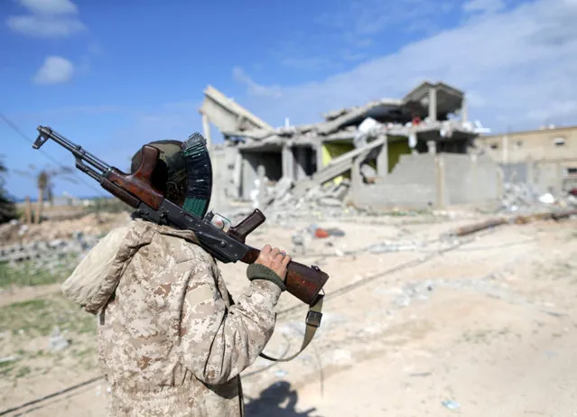 A member of East Libyan forces holds his weapon as he stands in front of a destroyed house in Ganfouda district in Benghazi, Libya, January 28, 2017. (Photo by Esam Omran Al-Fetori/Reuters)