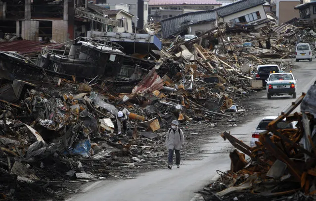 In this March 23, 2011 file photo, a resident walks between the rubble caused by the March 11 tsunami at Kesennuma, Miyagi Prefecture, northern Japan. (Photo by Shizuo Kambayashi/AP Photo)