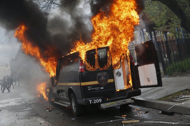A Baltimore Metropolitan Police transport vehicle burns during clashes in Baltimore, Maryland April 27, 2015. (Photo by Shannon Stapleton/Reuters)