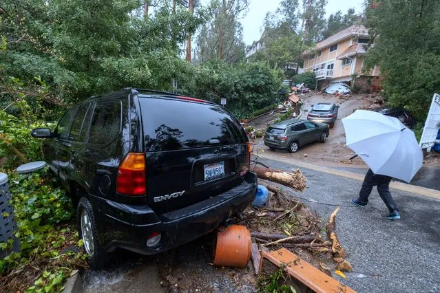 Debris is left after a flash flood and landslide smashed through the garage of a house in the distance as the second and more powerful of two atmospheric river storms, and likely the biggest storm of the season, inundates the Studio City section of Los Angeles, California, on February 5, 2024. Swaths of the US state of California were flooded on Monday and hundreds of thousands of people were without power after a dangerous storm brought heavy rains and prompted a state of emergency. (Photo by David McNew/AFP Photo)