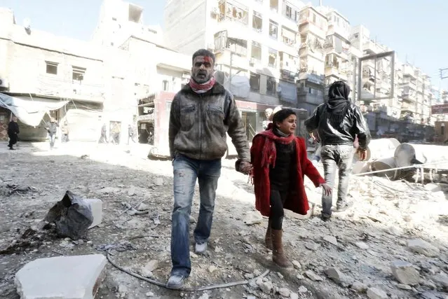 A bleeding man walks with a girl on debris after what activists said was shelling by forces loyal to Syria's President Bashar al-Assad in Aleppo's al-Shaar district February 3, 2014. (Photo by Saad Abobrahim/Reuters)