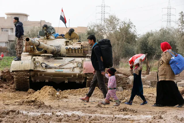 A family walks next to an Iraqi tank during a fight with Islamic State militants in Rashidiya, North of Mosul, Iraq, January 30, 2017. (Photo by Muhammad Hamed/Reuters)