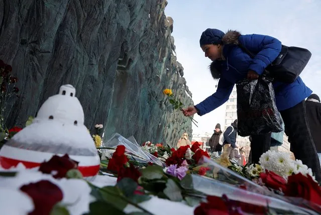 A woman lays flowers at the Wall of Grief monument to the victims of political repressions to honour the memory of Russian opposition leader Alexei Navalny in Moscow, Russia on February 17, 2024. (Photo by Reuters/Stringer)