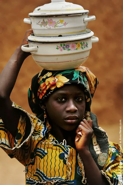 A Nigerian girl carries pots on her head in a remote area of Nigeria's Muslim north April 9, 2005 in Rimin Gado, Nigeria.  Polio, a disease that health workers once had hoped to eradicate worldwide by 2005, is on the march again in Nigeria, especially in this region, where local Islamic leaders banned the polio vaccine two years ago over post September 11 suspicions of everything Western. Inoculations have resumed and Nigeria will undertake a massive countrywide push to inoculate every child under five with nearly 4 million doses of polio vaccine in four days