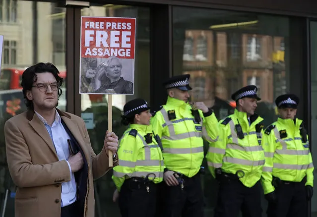 A protester demonstrating in support of WikiLeaks founder Julian Assange holds a placard outside Westminster magistrates court where he was appearing in London, Thursday, April 11, 2019. Police in London arrested WikiLeaks founder Assange at the Ecuadorean embassy Thursday, April 11, 2019 for failing to surrender to the court in 2012, shortly after the South American nation revoked his asylum. (Photo by Matt Dunham/AP Photo)