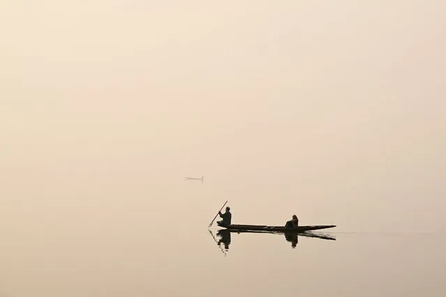 A man steers a boat across Dal Lake on a foggy day in Srinagar on December 12, 2023. (Photo by Tauseef Mustafa/AFP Photo)