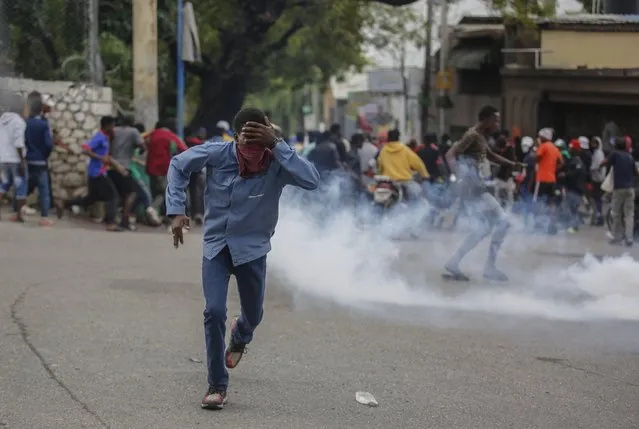 A protester run from tear gas fired by riot police officers during a demonstration demanding the resignation of Prime Minister Ariel Henry in Port-au-Prince, Haiti, Wednesday, February 7, 2024. (Photo by Odelyn Joseph/AP Photo)