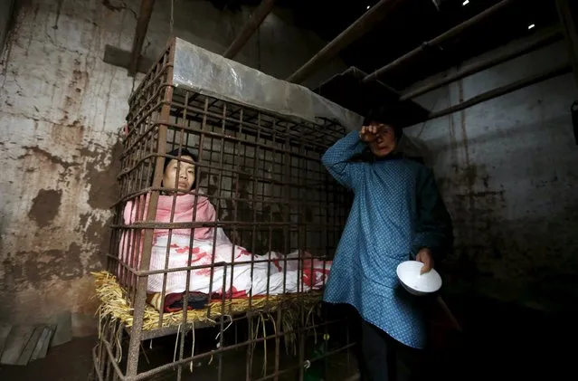Zhao Xiaoyang's mother wipes her tears as Zhao sits inside a cage after having breakfast at their home in Fangjia village, Zhejiang province May 6, 2015. Zhao has been living in a cage after he was diagnosed with mental disorder in 2001 and had beaten a man to death. For years, his mother cooks him meals and takes care of his personal hygiene. (Photo by William Hong/Reuters)