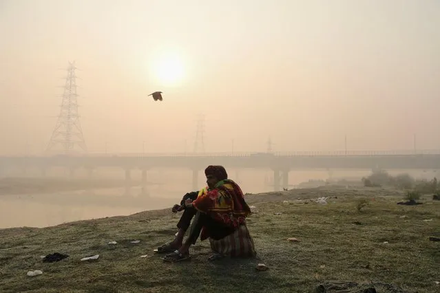 A man sits on the banks of the Yamuna river on a smoggy morning in New Delhi, India, November 19, 2021. (Photo by Anushree Fadnavis/Reuters)