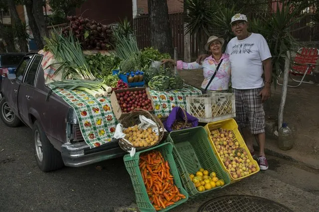 Nancy Espinoza, 55, and her husband Aurelio Espinoza, 60, pose for aphoto next to their new business, selling vegetables using an old car s stand, in Caracas, Venezuela, Friday, May 3, 2019.  “With the Bolivarian Revolution we have entered a primitive state, we've gone back 150 years.  We are now in ruins and the country its mortgaged to the Russians and the Chinese”. said the 60-year-old. (Photo by Rodrigo Abd/AP Photo)