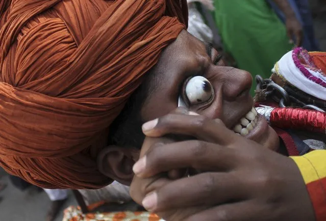 An Indian Muslim devotee on a pilgrimage to the shrine of Sufi saint Khwaja Moinuddin Chishti for the festival of Urs, performs a stunt during a procession at Ajmer in the desert Indian state of Rajasthan April 8, 2016. The annual festival of Urs is held for over six days at Ajmer to commemorate the death anniversary of Sufi saint Chishti. (Photo by Himanshu Sharma/Reuters)