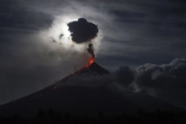 The “super blue blood moon” obscured by clouds illuminates Mayon volcano as it spews ash near Legazpi City, Albay province, early on February 1, 2018. Skywatchers were hoping for a rare lunar eclipse that combines three unusual events – a blue moon, a super moon and a total eclipse, which was to make for a large crimson moonviewable in many corners of the globe. (Photo by Ted Aljibe/AFP Photo)