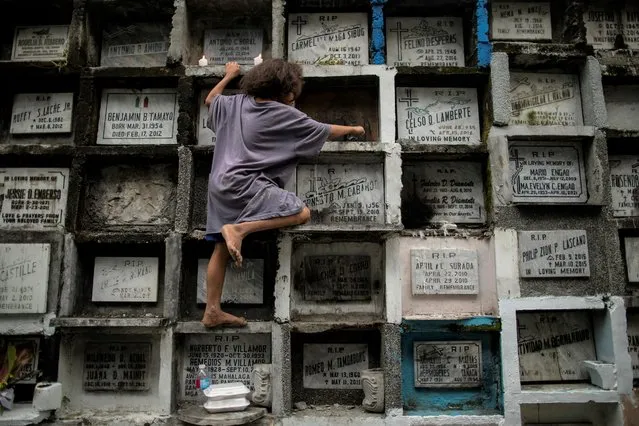 A child cleans melted candle wax from an apartment-style grave at Manila South Cemetery a day before the nationwide cemetery closure during All Saints' Day amid the coronavirus disease (COVID-19) outbreak, in Manila, Philippines, October 28, 2021. (Photo by Eloisa Lopez/Reuters)