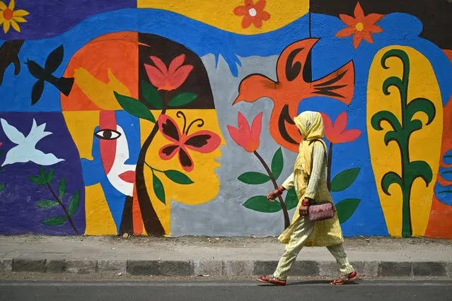 A woman walks past a mural along a a street in New Delhi on April 12, 2024. (Photo by Arun Sankar/AFP Photo)