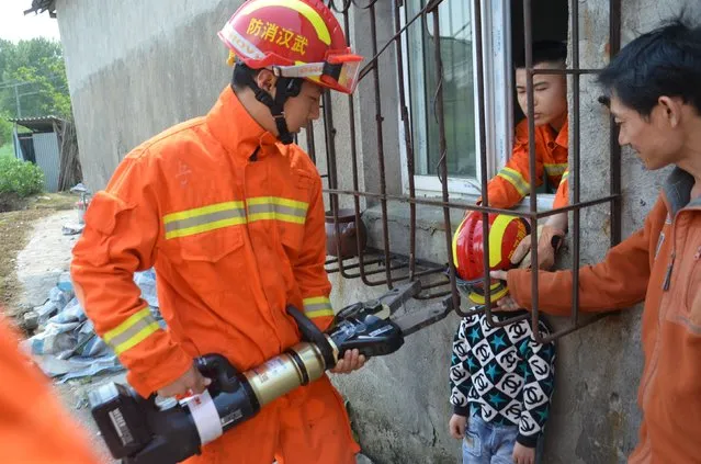 Firemen rescue a boy whose head is stuck between protective bars outside a window in Wuhan, Hubei Province, China, in this April 11, 2016 picture. (Photo by Reuters/Stringer)