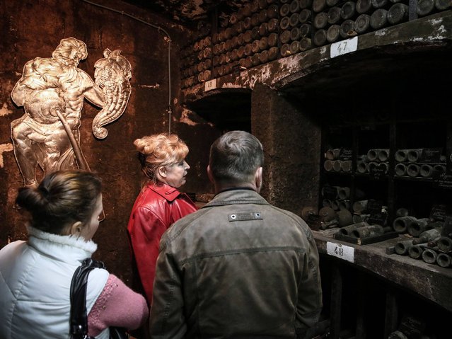 A worker of the Massandra winery and museum speaks to visitors during a guided tour to the museum gallery of vintage wines through the wine cellars of the winery in Massandra village near Yalta. (Photo by Sergei Ilnitsky/EPA)