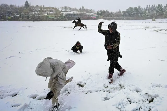 Youths play in the snow during a snowfall at the Qargha lake in Kabul on January 3, 2022. (Photo by Mohd Rasfan/AFP Photo)