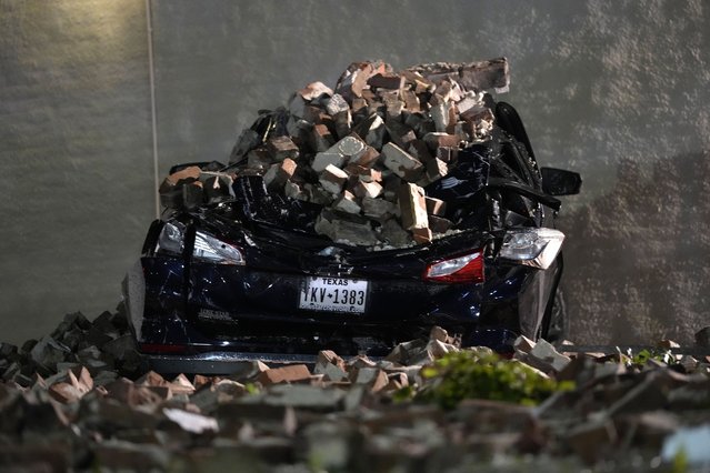 A car crushed by falling bricks from a fallen building wall sits in a downtown parking lot after a severe thunderstorm passed through, Thursday, May 16, 2024, in Houston. (Photo by David J. Phillip/AP Photo)