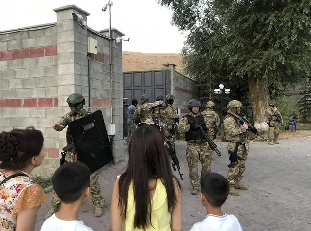 Kyrgyz special forces stand in guard at former president of Kyrgyzstan Almazbek Atambayev's residence in the village of Koi-Tash, about 20 kilometers (12 miles) south of the capital, Bishkek, Kyrgyzstan, Wednesday, August 7, 2019. Gunfire is being heard outside the residence of the former president of Kyrgyzstan as police move in to try to arrest him. The Kyrgyz news site 24.kg said several people, including journalists, have been wounded in the Wednesday shooting in the village of Koi-Tash, 20 kilometers (12 miles) south of the capital, Bishkek. (Photo by AKIpress via AP Photo)