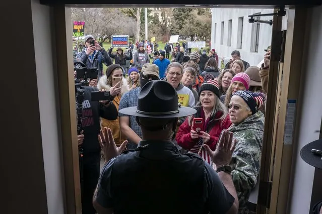 Attendees at a rally against vaccine and mask mandates argue with Oregon state troopers while trying to enter the state capitol on February 1, 2022 in Salem, Oregon. After listening to speakers outside the building, the crowd was successful in getting state troopers to let some maskless members into the statehouse. (Photo by Nathan Howard/Getty Images/AFP Photo)